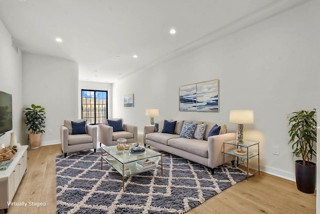 living area featuring light wood-type flooring, baseboards, and recessed lighting