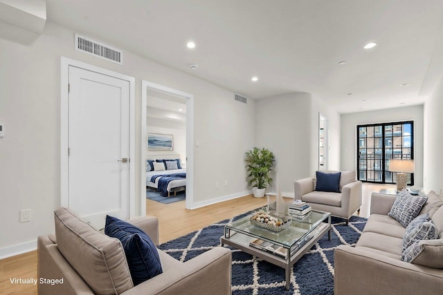 living room with light wood-type flooring, visible vents, and recessed lighting