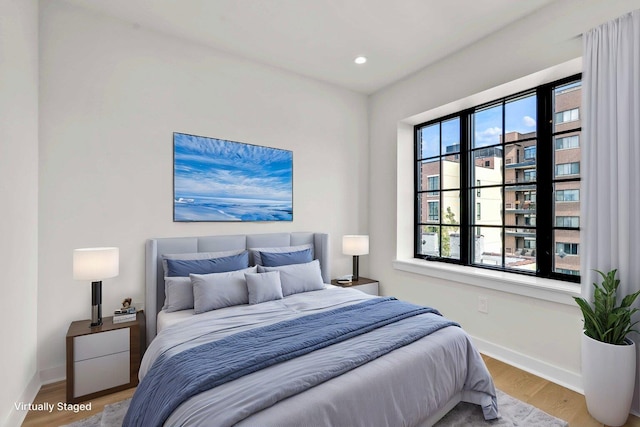 bedroom with recessed lighting, wood finished floors, and baseboards