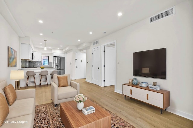 living room featuring recessed lighting, visible vents, light wood-style flooring, and baseboards