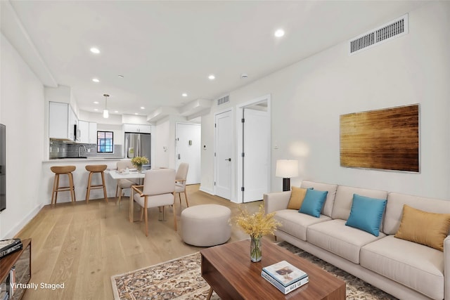 living area featuring baseboards, visible vents, recessed lighting, and light wood-type flooring