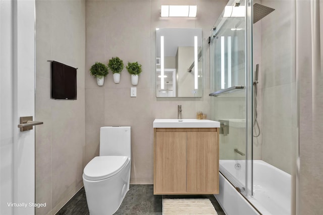 full bath featuring tile walls, combined bath / shower with glass door, toilet, and vanity