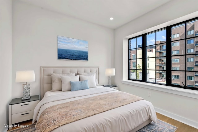 bedroom with baseboards, wood finished floors, and recessed lighting