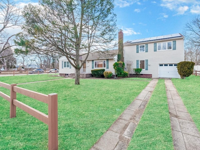 view of front facade with a chimney, an attached garage, a front yard, fence, and driveway