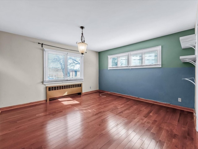 spare room with radiator, wood-type flooring, and baseboards