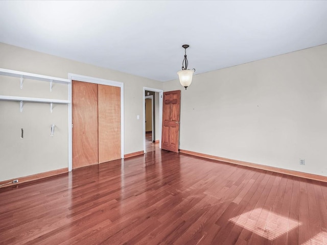 unfurnished bedroom featuring a closet, baseboards, and wood finished floors