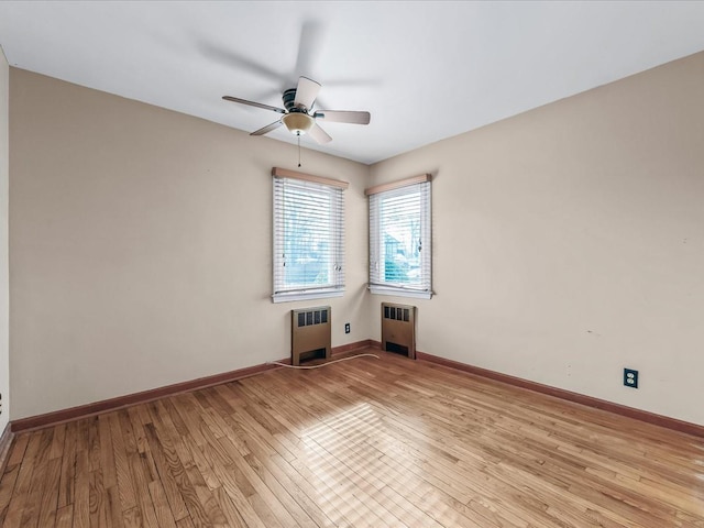 spare room with light wood-type flooring, baseboards, and radiator heating unit