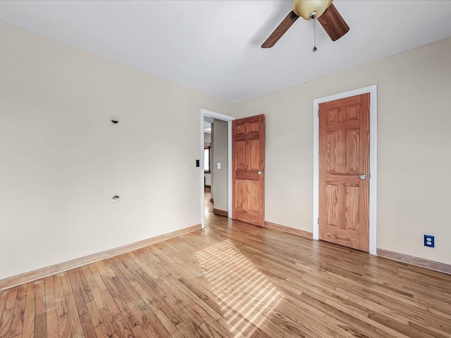 empty room with a ceiling fan, light wood-style flooring, and baseboards