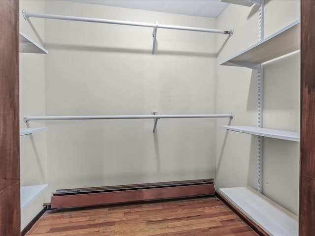 walk in closet featuring baseboard heating and wood finished floors