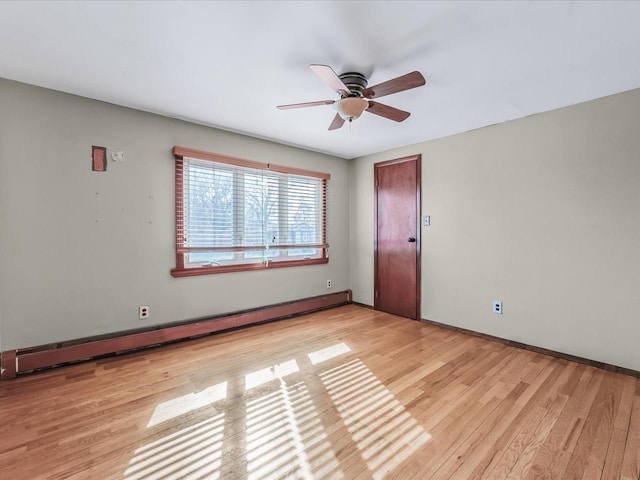 spare room featuring a baseboard radiator, baseboards, ceiling fan, and wood finished floors