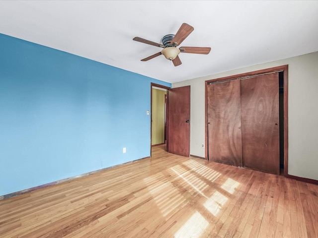 unfurnished bedroom featuring ceiling fan, a closet, baseboards, and light wood-style floors