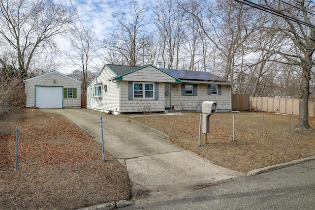 view of front facade featuring a garage, concrete driveway, solar panels, fence, and an outdoor structure