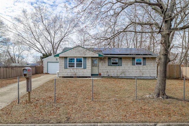 ranch-style house with driveway, a garage, roof mounted solar panels, and fence