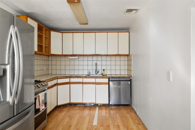 kitchen featuring stainless steel appliances, white cabinets, a sink, and visible vents