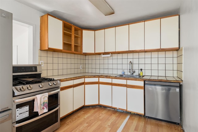 kitchen featuring light wood-style floors, white cabinetry, appliances with stainless steel finishes, and a sink