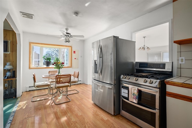 kitchen with light wood-style flooring, stainless steel appliances, visible vents, hanging light fixtures, and tile counters