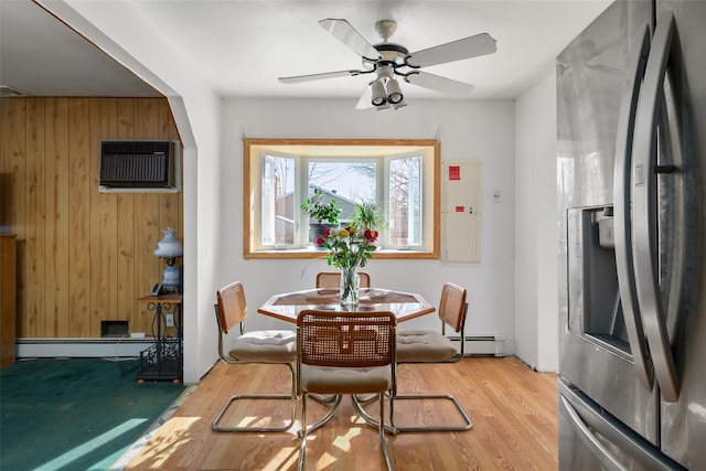 dining room with ceiling fan, a wall unit AC, light wood-style flooring, a baseboard heating unit, and wood walls