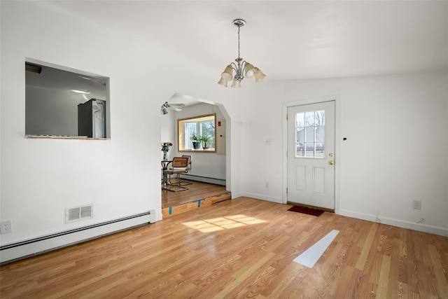 foyer with arched walkways, baseboard heating, a baseboard radiator, and wood finished floors