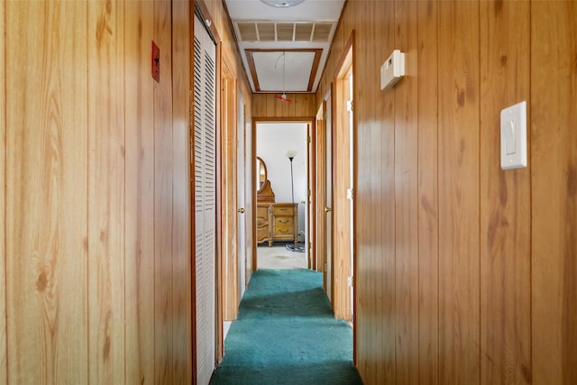 corridor with attic access, wooden walls, visible vents, and carpet flooring