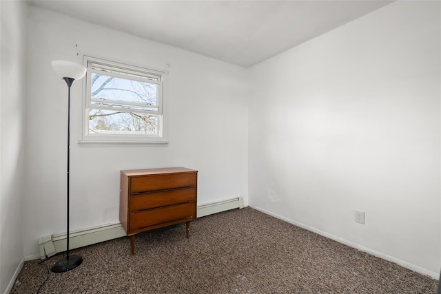 spare room with dark colored carpet, baseboards, and baseboard heating