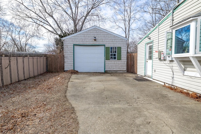 detached garage with concrete driveway and fence