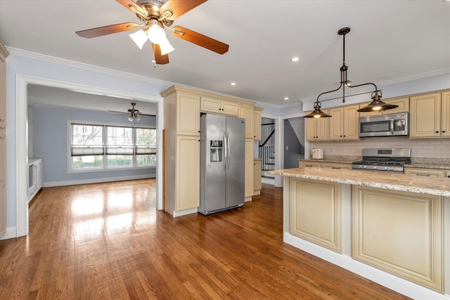 kitchen with ornamental molding, appliances with stainless steel finishes, and cream cabinets