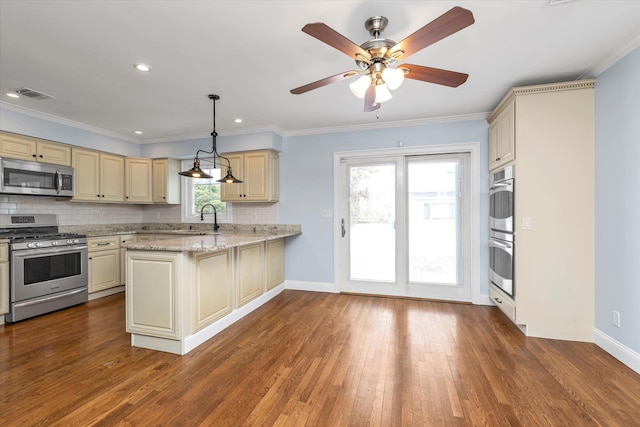 kitchen with appliances with stainless steel finishes, cream cabinets, a sink, and visible vents