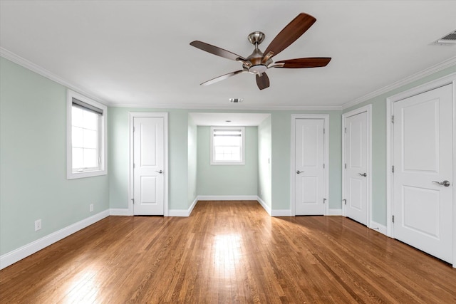 unfurnished bedroom with wood-type flooring, visible vents, baseboards, and two closets