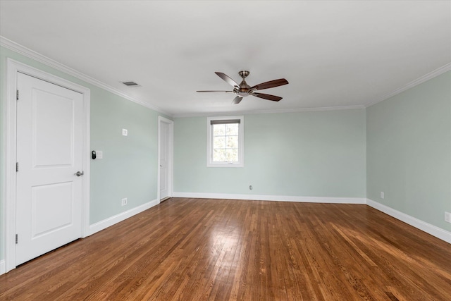 spare room featuring baseboards, wood finished floors, and crown molding