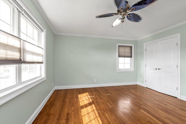 spare room with baseboards, wood finished floors, and crown molding