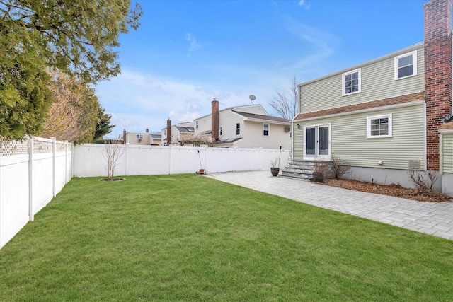 view of yard with entry steps, a patio area, a fenced backyard, and french doors