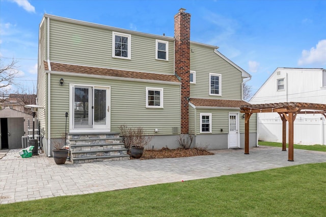 back of property featuring entry steps, a chimney, fence, a patio area, and a pergola