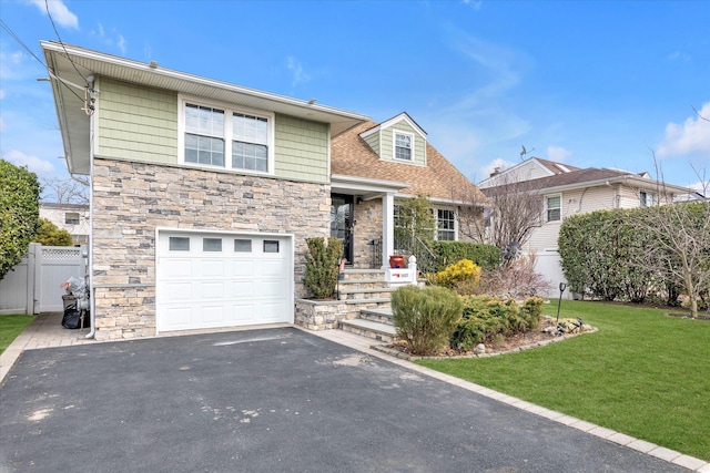 view of front facade with aphalt driveway, a front yard, fence, a garage, and stone siding