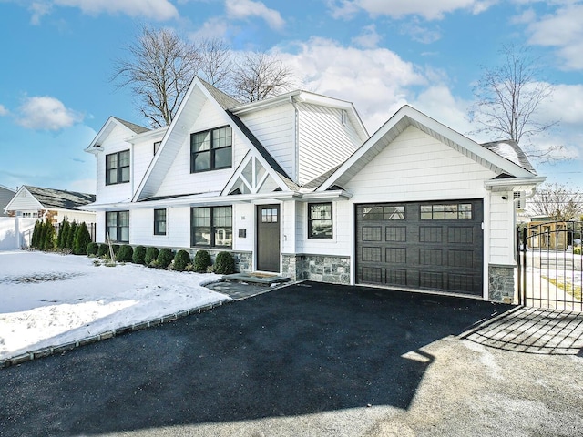 view of front of home with a garage, stone siding, aphalt driveway, and fence