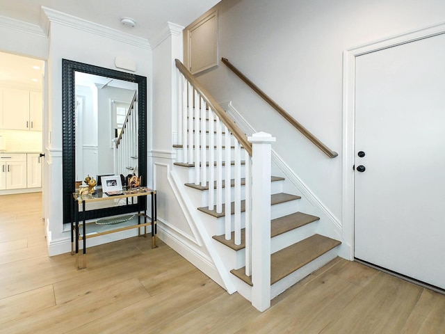 stairway featuring ornamental molding and wood finished floors