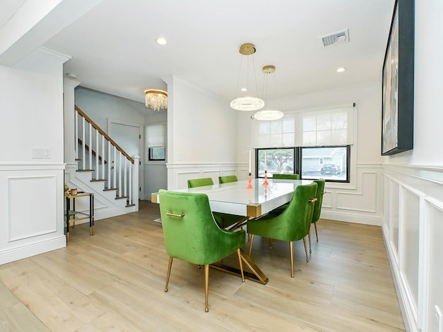 dining room featuring light wood-style floors, stairway, visible vents, and a decorative wall