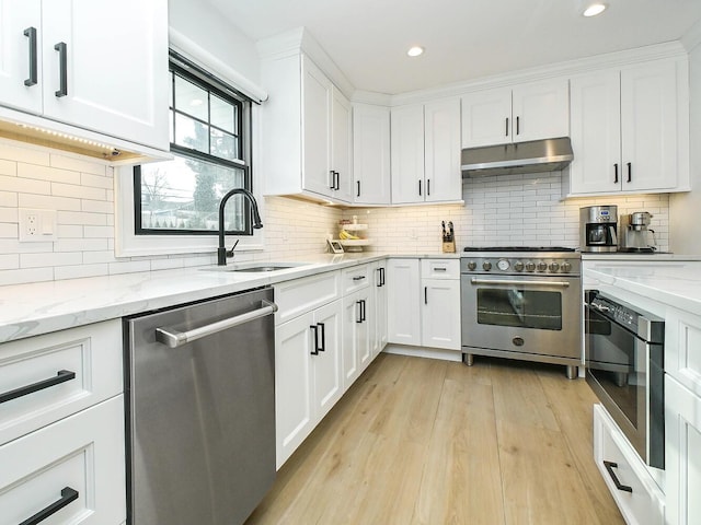 kitchen featuring white cabinets, light wood-style flooring, appliances with stainless steel finishes, under cabinet range hood, and a sink