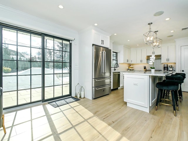 kitchen featuring stainless steel appliances, white cabinetry, light countertops, tasteful backsplash, and crown molding