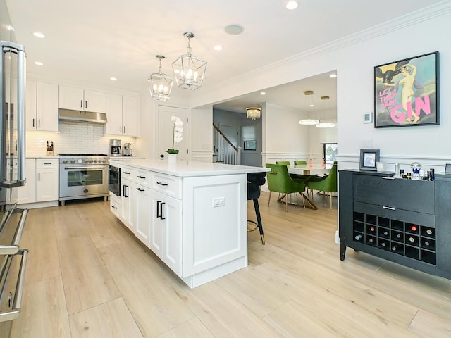 kitchen with under cabinet range hood, white cabinetry, and stainless steel range