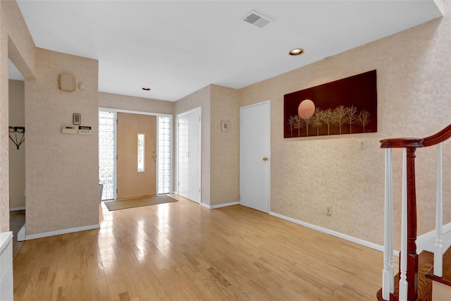 entrance foyer with stairway, baseboards, visible vents, and wood finished floors