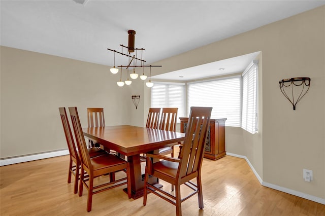 dining room featuring a baseboard heating unit, light wood finished floors, and baseboards