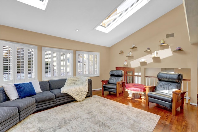 living area with lofted ceiling with skylight, visible vents, baseboards, and wood finished floors