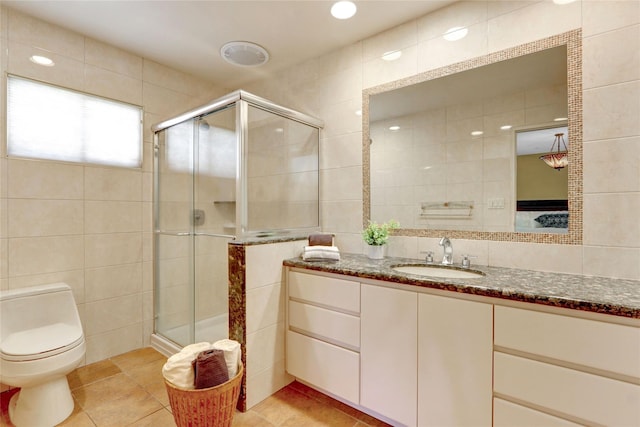 full bathroom with toilet, vanity, tile walls, tile patterned floors, and a stall shower