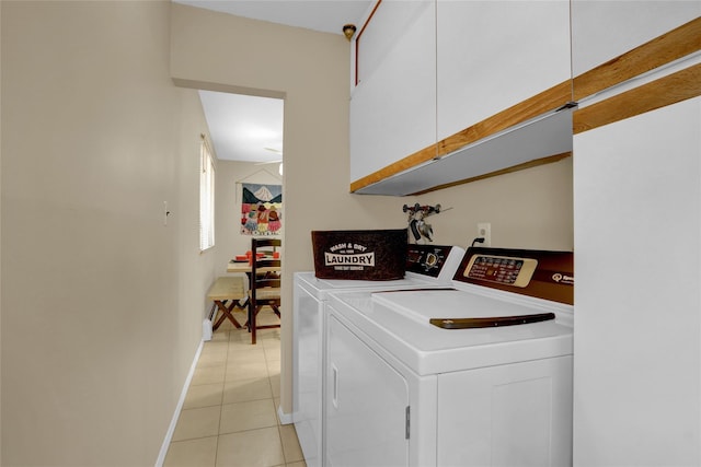 laundry room with light tile patterned floors, separate washer and dryer, cabinet space, and baseboards