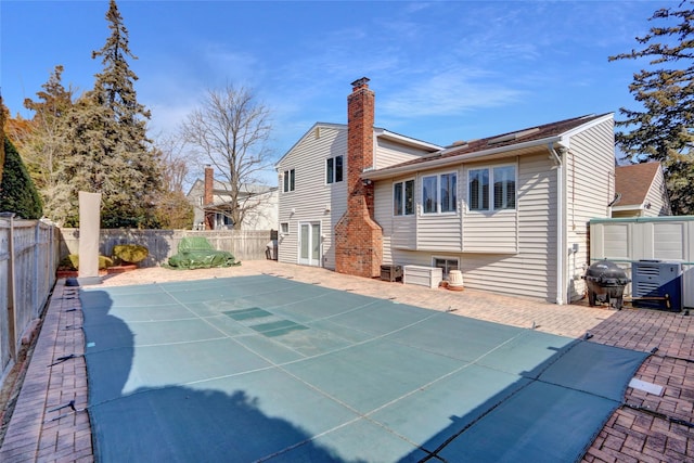 rear view of house featuring a patio area, a fenced backyard, and a chimney