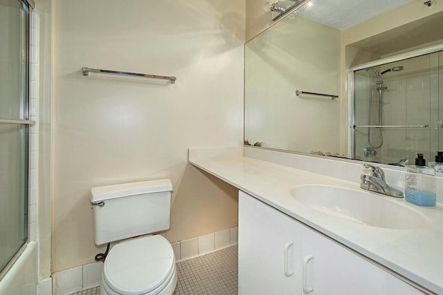 full bath featuring baseboards, toilet, shower / bath combination with glass door, tile patterned flooring, and vanity