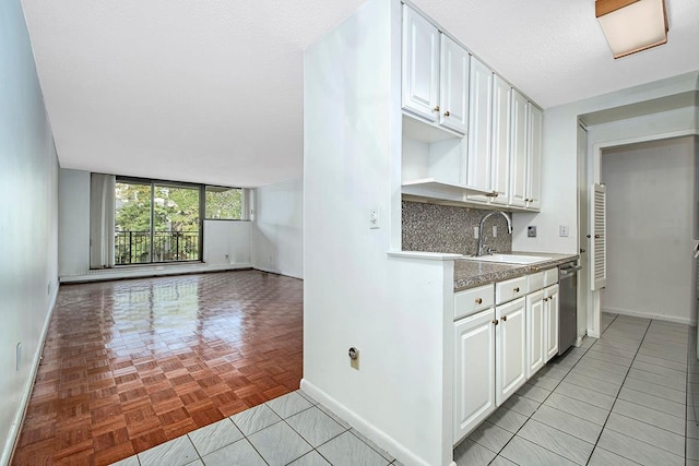 kitchen featuring tasteful backsplash, white cabinets, a sink, a textured ceiling, and dishwasher