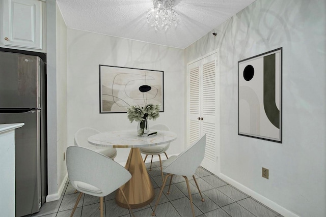 dining space featuring light tile patterned floors, a textured ceiling, and baseboards