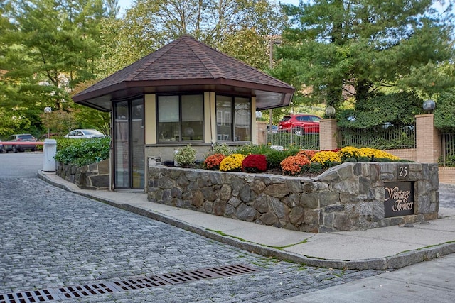 view of front facade featuring fence and roof with shingles