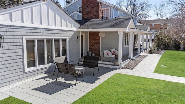 back of property featuring a chimney, an outdoor living space, a lawn, and a patio